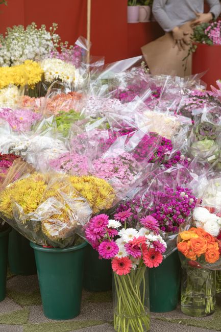 An arrangement of fresh flowers displayed at floristchiswick.co.uk, featuring vibrant pink, orange, yellow, and white blooms including daisies, chrysanthemums, and roses. The flowers are arranged in v